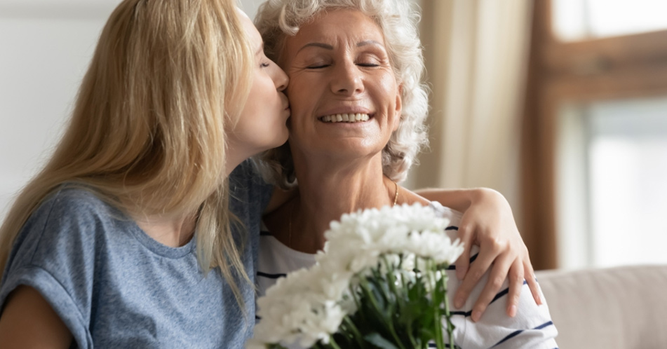 Image of a woman gifting her senior mother with a bouquet of fresh flowers