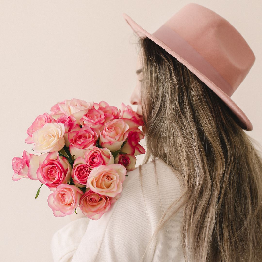 person in a hat holding a bouquet of roses